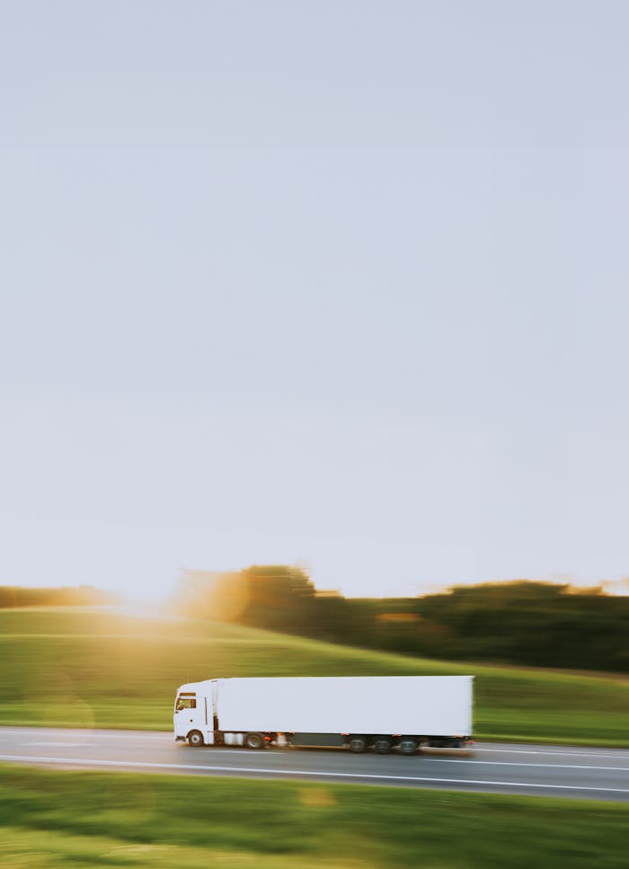team-03 White cargo truck speeding through Vitebsk countryside at sunrise, symbolizing transportation and logistics.